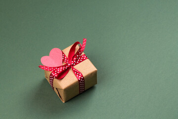 Gift box with bow and paper heart on a green background. Valentine's Day.