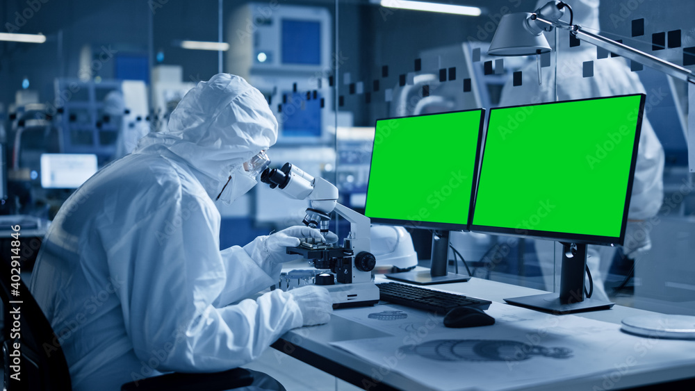 Poster research factory cleanroom: close-up of engineer / scientist wearing coverall and gloves uses micros