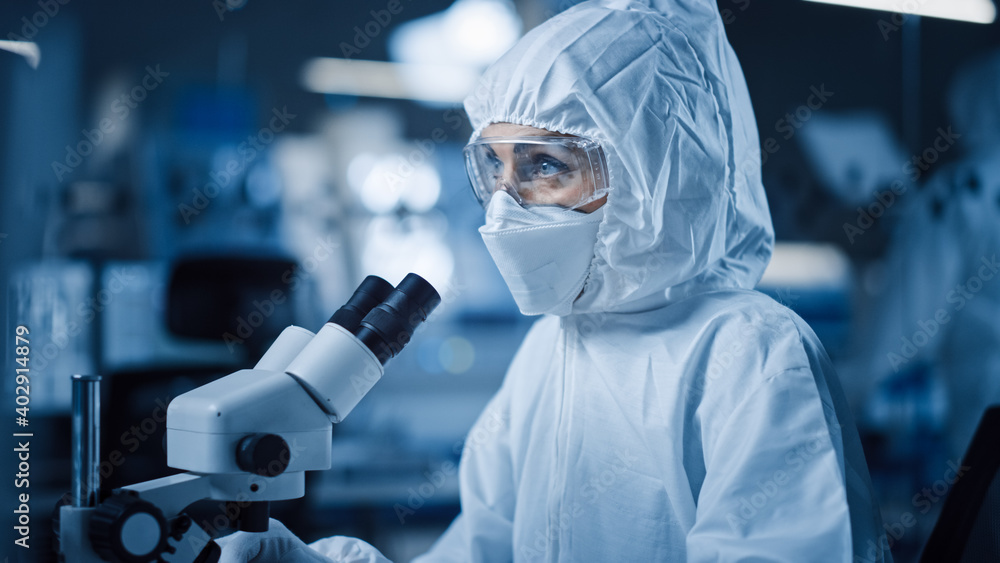 Leinwandbilder research factory cleanroom: engineer / scientist wearing coverall and uses microscope to inspect sam
