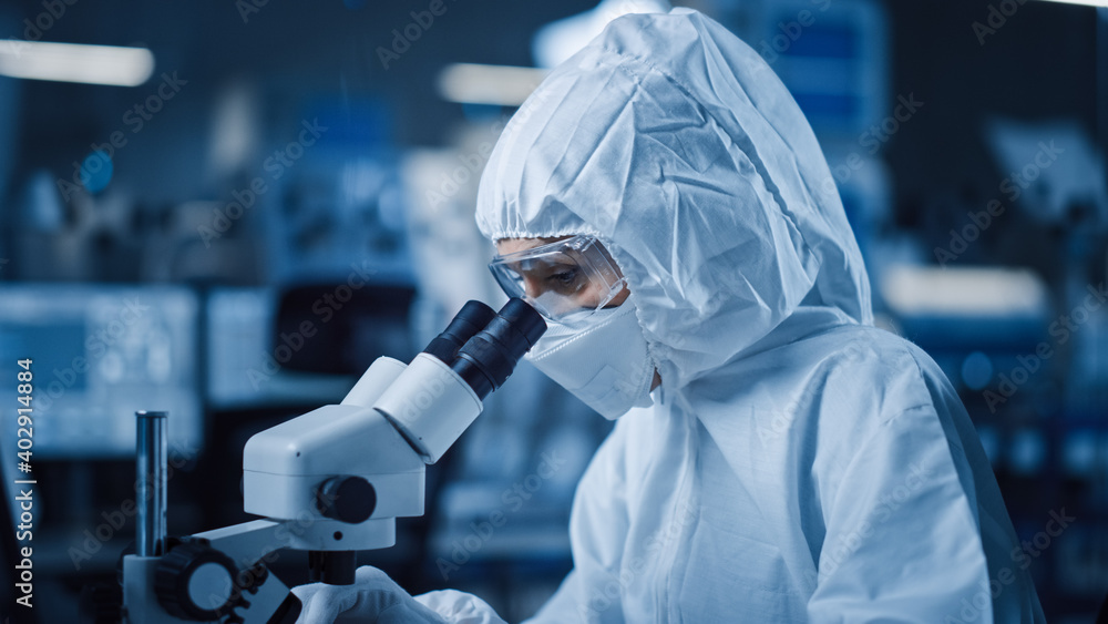Fototapete research factory cleanroom: engineer / scientist wearing coverall and uses microscope to inspect sam