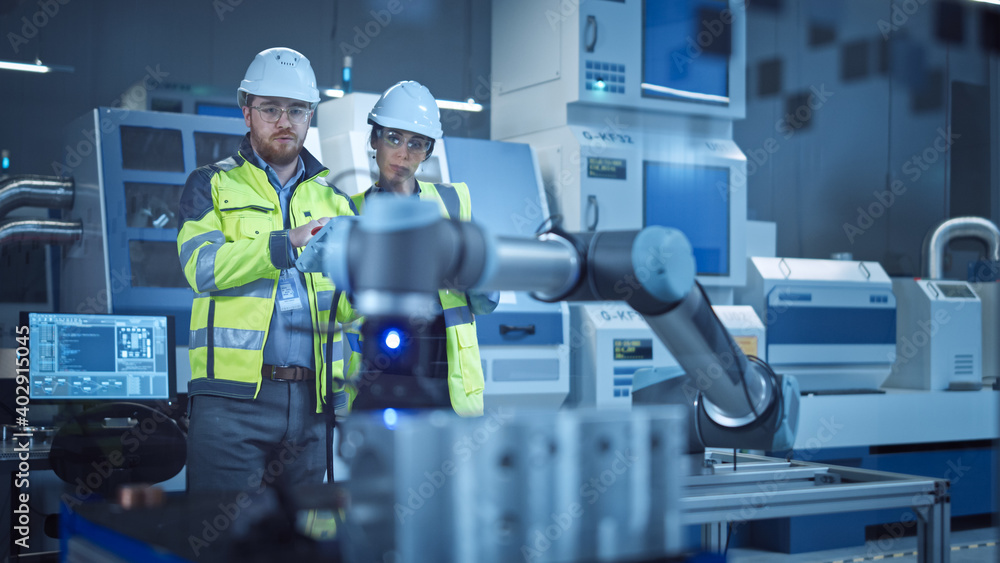Poster Factory Workshop: Professional Female Engineer, Male Machinery Operator Use Industrial Digital Tablet Computer to Work and Program Robot Arm for Production Line. High-Tech Facility with CNC Machines