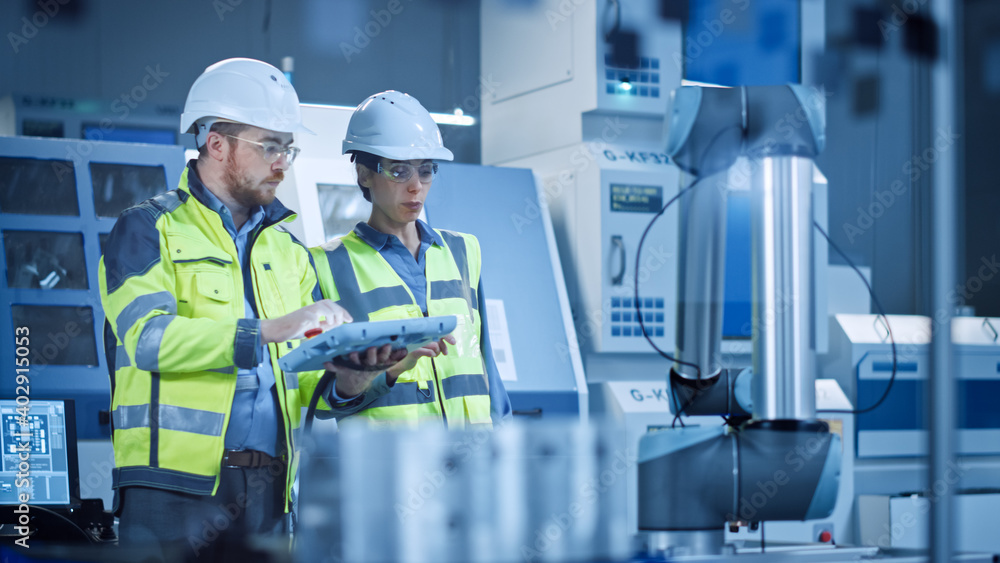 Poster Factory Workshop: Professional Female Engineer, Male Machinery Operator Use Industrial Digital Tablet Computer to Work and Program Robot Arm for Production Line. High-Tech Facility with CNC Machines