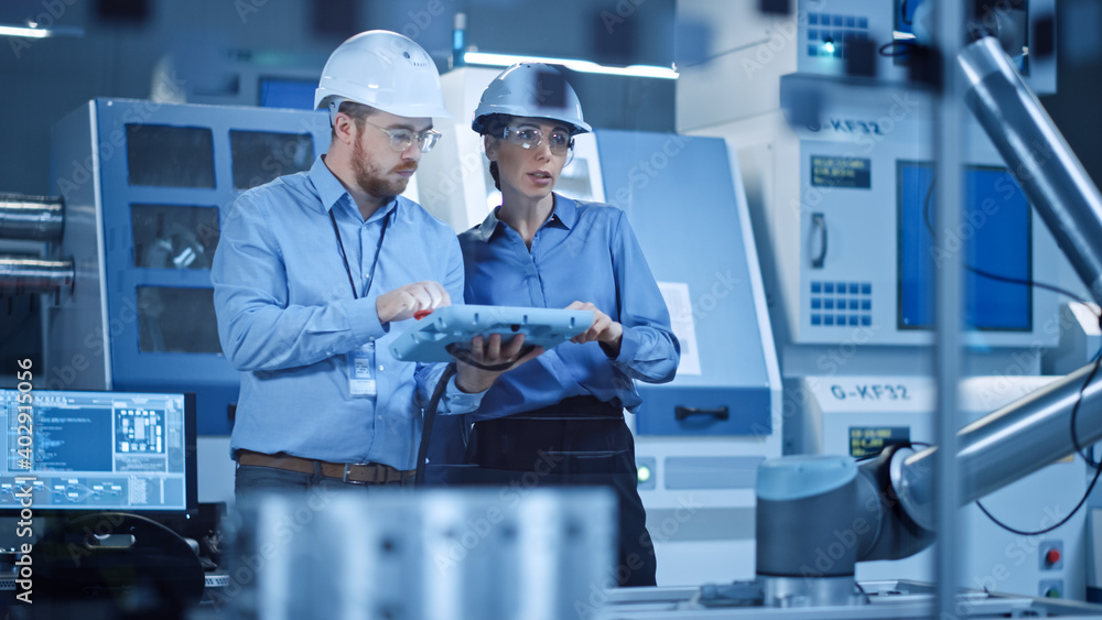 Poster Factory Workshop: Professional Female Engineer, Male Machinery Operator Use Industrial Digital Tablet Computer to Work and Program Robot Arm for Production Line. High-Tech Facility with CNC Machines