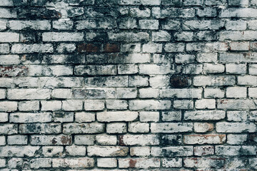 Aged white painted brick wall texture. Old textured grunge wall surface background pattern of masonry. Cracks and black stains.