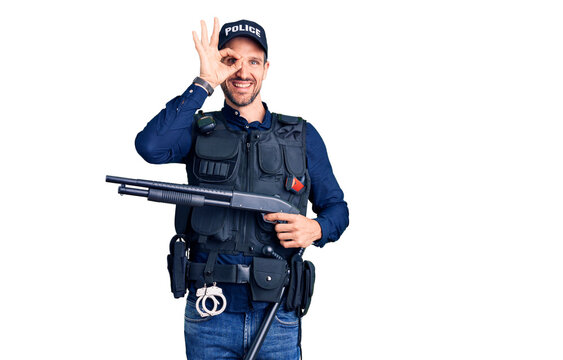 Young handsome man wearing police uniform holding shotgun doing ok sign with fingers, smiling friendly gesturing excellent symbol