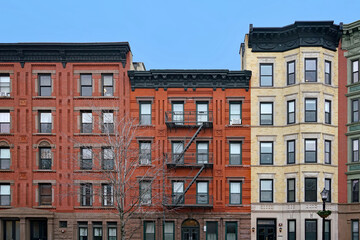 Old New York apartment buildings with ornate roof line cornice and exterior fire escape ladder