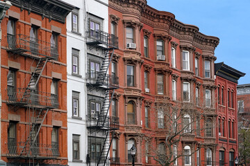 Old New York apartment buildings with ornate roof line cornice and exterior fire escape ladder