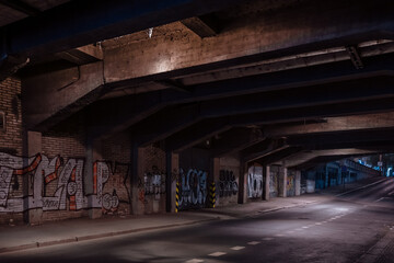 Fototapeta na wymiar Dark empty dirty grunge underground concrete tunel with a road during mystic night with blue street lights