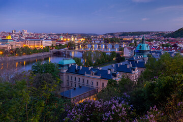 View on downtown Prague bridges and river from romantic Letna view point during early sunset with yellow street lights and blue sky, Prague, Czechia, Europe