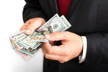 Closeup of businessman's hands counting US dollars bills. Man counting bunch of money on white background. Spending, saving, earning money concept. Getting salary. Company profit, investment earnings.