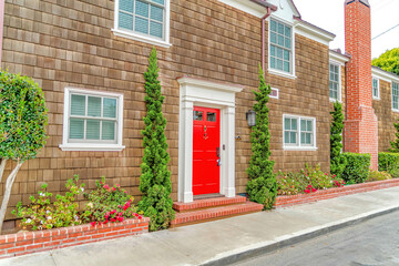 Facade of two storey home in Long Beach CA with red front door and wall shingles
