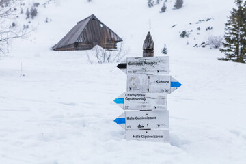 Polskie Tatry, niemal w całości pokryty śniegiem drogowskaz pokazujący kierunki szlaków na Świnicę, Halę Gąsienicową, Kuźnice © lukszczepanski