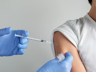 Close-up on hands in gloves with syringe and shoulder of the patient, teen kid. Coronavirus, flu or...