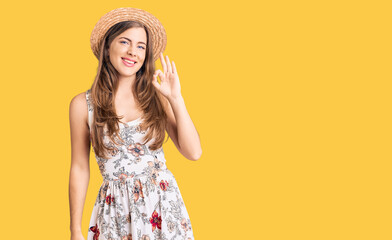 Beautiful caucasian young woman wearing summer hat smiling positive doing ok sign with hand and fingers. successful expression.