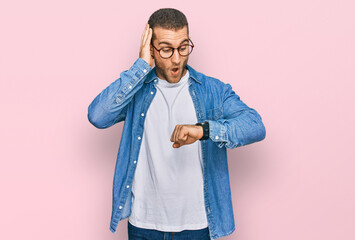 Young caucasian man wearing casual clothes looking at the watch time worried, afraid of getting late