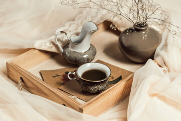 Morning coffee. Cup of coffee on a wooden tray on a silk bed. Still life concept.Home interior, lifestyle. Selective focus