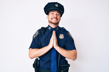 Young caucasian man wearing police uniform begging and praying with hands together with hope expression on face very emotional and worried. begging.