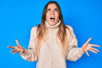 Beautiful caucasian woman wearing wool winter sweater crazy and mad shouting and yelling with aggressive expression and arms raised. frustration concept.