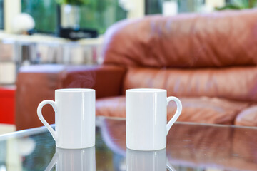 Two cups of tea or coffee together on a coffee table in a light home interior room