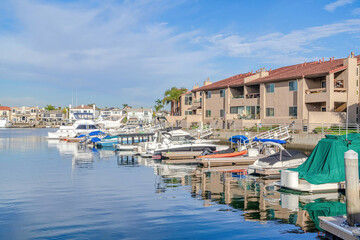 Fototapeta na wymiar Boats docked at the harbour with waterfront homes in Huntington Beach California