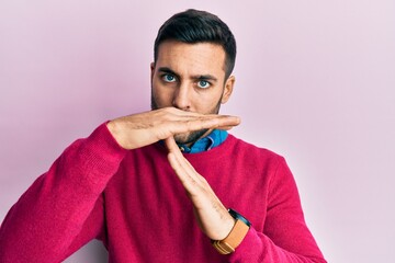 Young hispanic man wearing casual clothes doing time out gesture with hands, frustrated and serious...