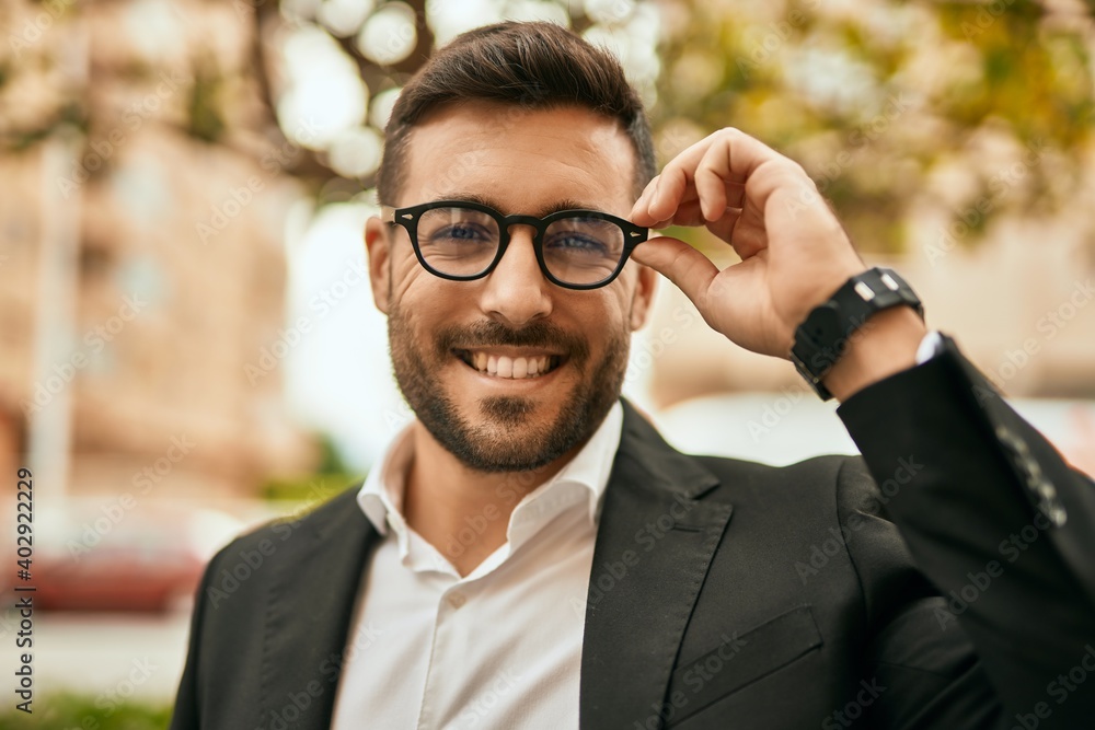 Poster Young hispanic businessman smiling happy standing at the city.