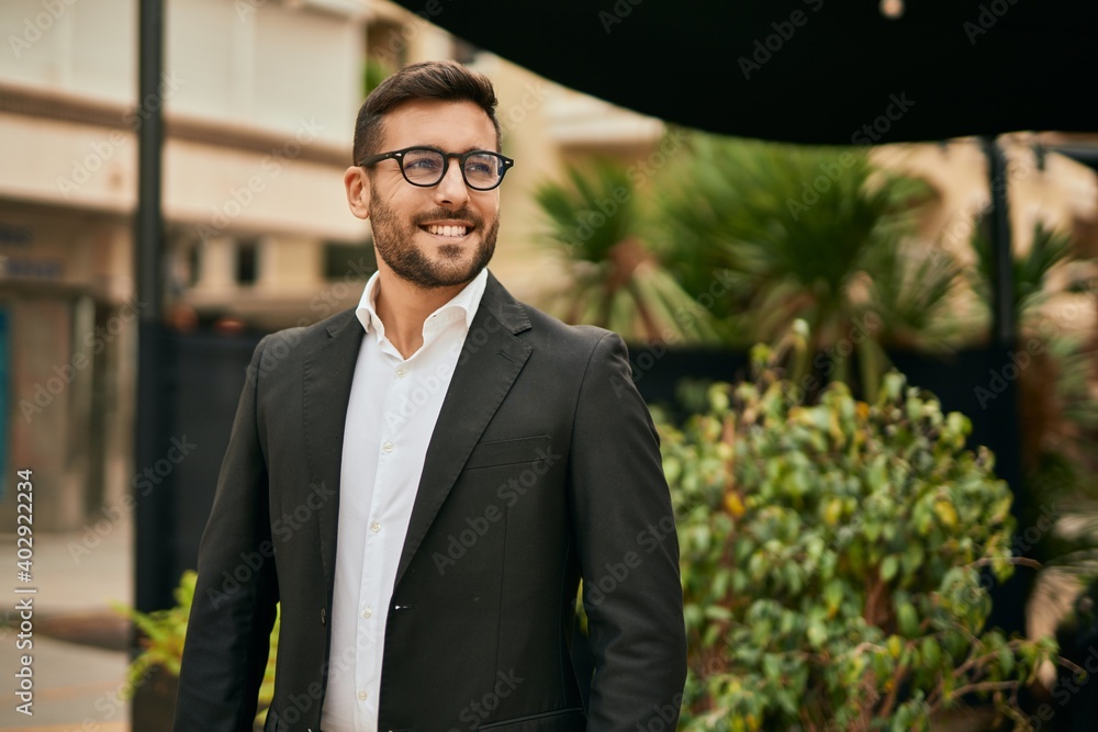 Wall mural young hispanic businessman smiling happy standing at the city.