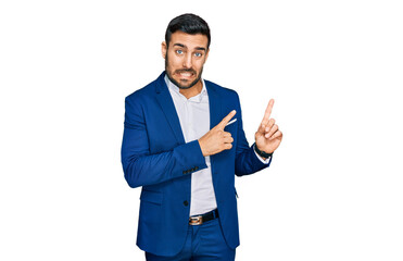 Young hispanic man wearing business jacket pointing aside worried and nervous with both hands, concerned and surprised expression