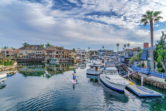 People on paddle boards against houses with private docks in Huntington Beach
