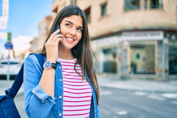 Young hispanic student girl smiling happy talking on the smartphone at the city.