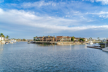 Fototapeta na wymiar Waterfront homes with private docks overlooking the sea under cloudy blue sky