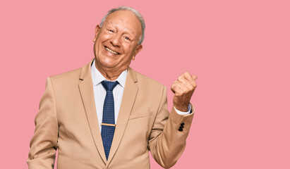 Senior caucasian man wearing business suit and tie smiling with happy face looking and pointing to the side with thumb up.