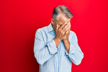 Middle age grey-haired man wearing casual clothes with sad expression covering face with hands while crying. depression concept.