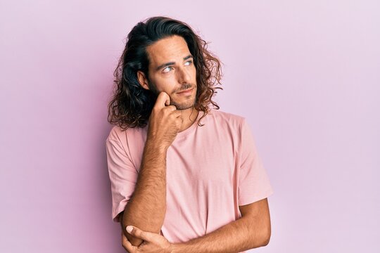 Young handsome man with long hair wearing casual clothes thinking concentrated about doubt with finger on chin and looking up wondering