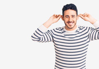 Young hispanic man wearing casual clothes smiling pulling ears with fingers, funny gesture. audition problem