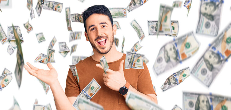 Young hispanic man wearing casual clothes amazed and smiling to the camera while presenting with hand and pointing with finger.