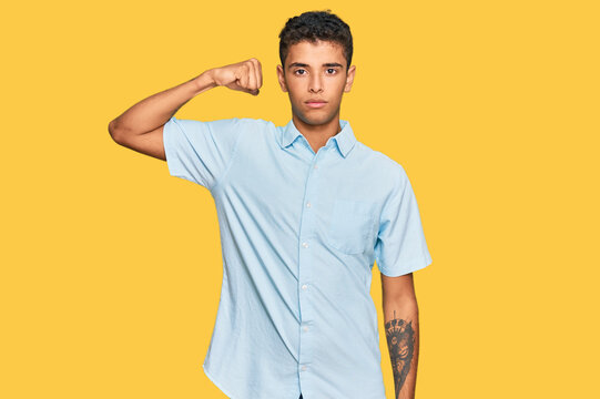 Young handsome african american man wearing casual clothes strong person showing arm muscle, confident and proud of power