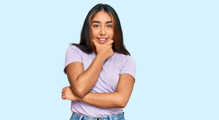 Obraz premium Young latin woman wearing casual clothes looking confident at the camera smiling with crossed arms and hand raised on chin. thinking positive.