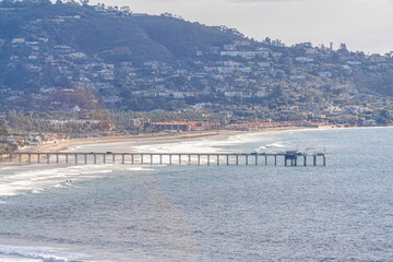 Fototapeta na wymiar Pier at the ocean of San Diego California with view of houses on mountain slope