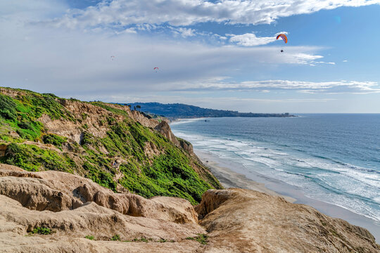 Steep rocky mountain overlooking parachuters and ocean in San Diego California
