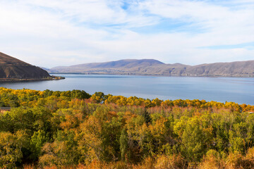 Sevan Lake in Armenia with beautiful trees in autumn colors. Alpine lake with mountains in the Caucasus. Popular Armenian touristic destination.