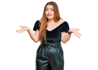 Young beautiful redhead woman wearing elegant clothes clueless and confused expression with arms...
