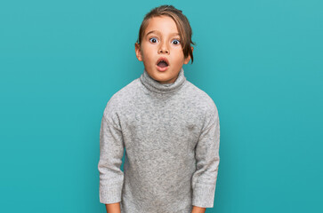 Little beautiful girl wearing casual turtleneck sweater scared and amazed with open mouth for...
