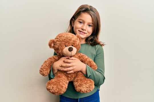 Naklejka Little beautiful girl hugging teddy bear smiling with a happy and cool smile on face. showing teeth.
