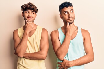 Fototapeta na wymiar Young gay couple wearing casual clothes with hand on chin thinking about question, pensive expression. smiling with thoughtful face. doubt concept.