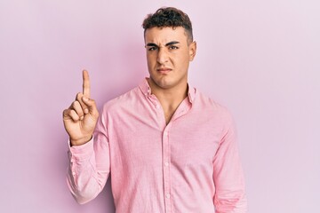 Hispanic young man pointing up with fingers clueless and confused expression. doubt concept.