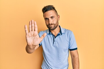 Handsome man with beard wearing casual clothes doing stop sing with palm of the hand. warning expression with negative and serious gesture on the face.