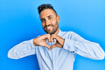 Handsome man with beard wearing casual clothes smiling in love doing heart symbol shape with hands. romantic concept.