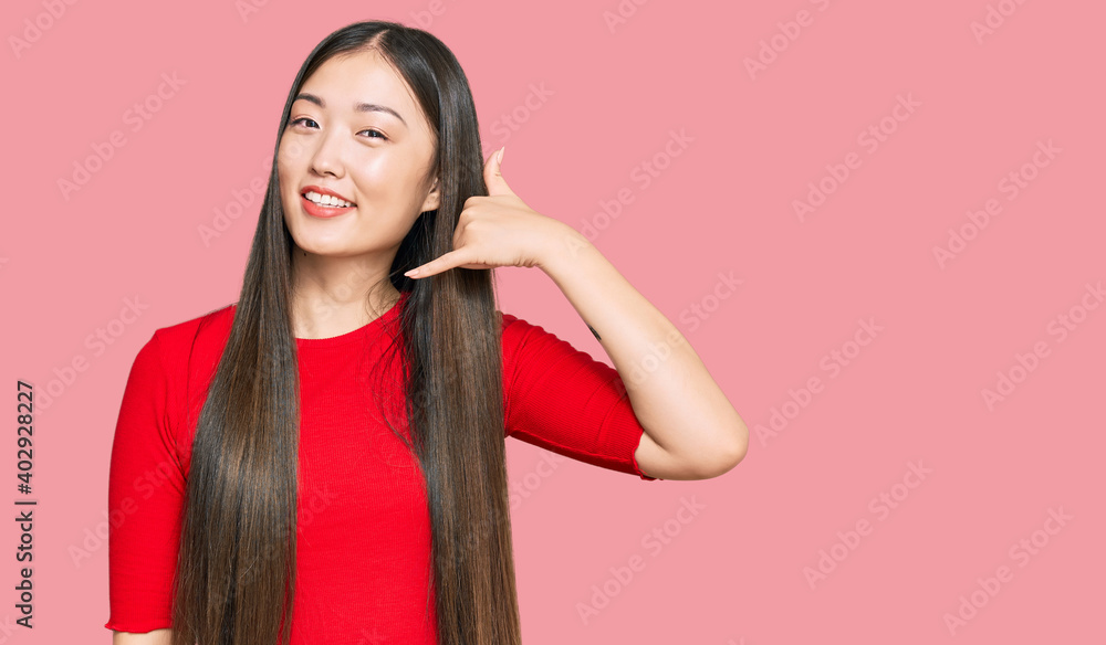 Canvas Prints Young chinese woman wearing casual clothes smiling doing phone gesture with hand and fingers like talking on the telephone. communicating concepts.