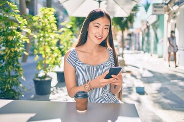 Young chinese woman smiling happy sitting on the table at street of city. © Krakenimages.com